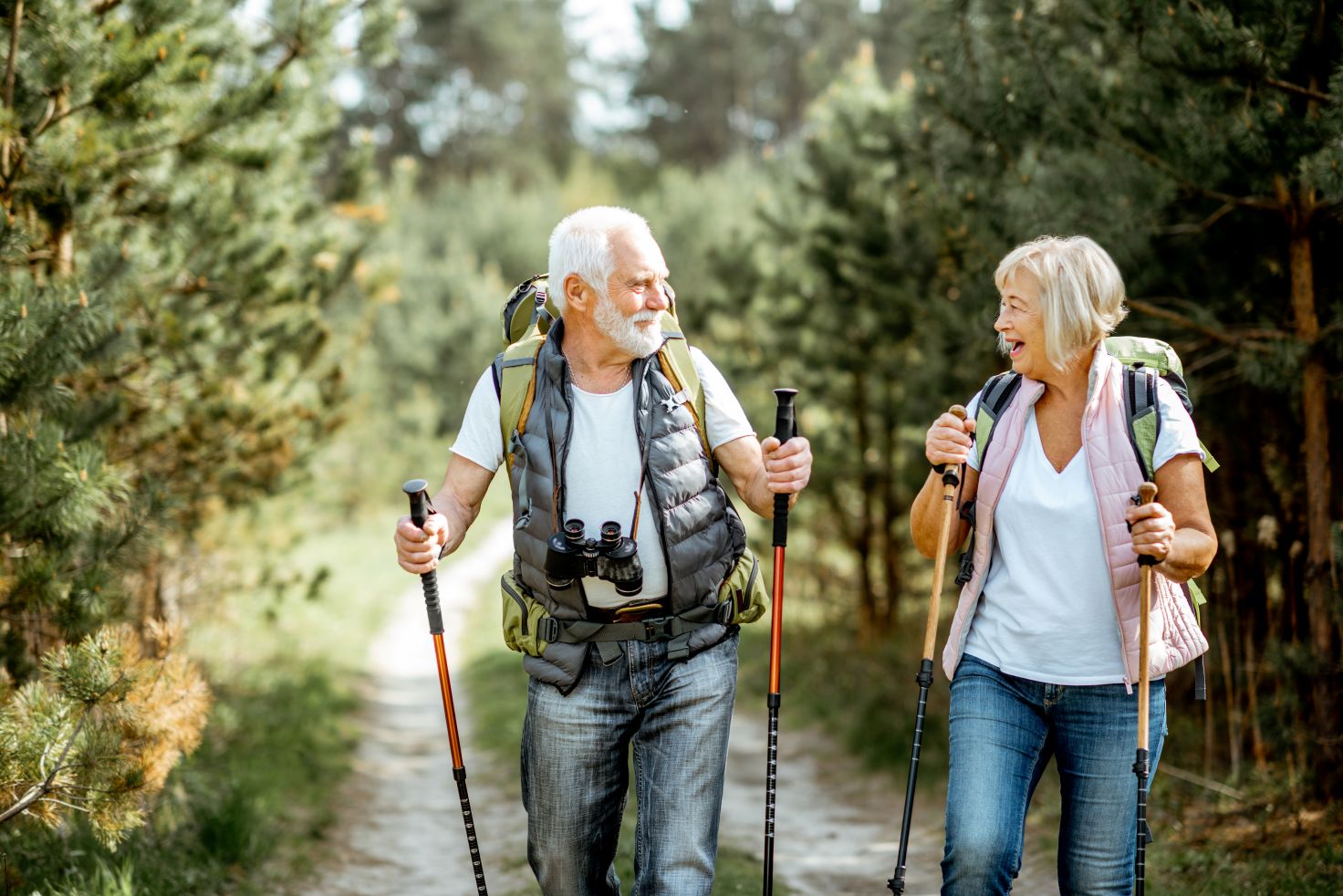 Ein älterer Mann und eine ältere Frau machen einen Spaziergang mit Walkingstöcken.