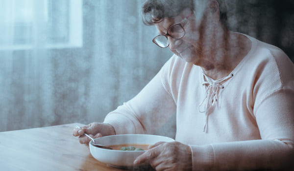 Eine Seniorin sitzt vor ihrem Essen und hat keinen Appetit.