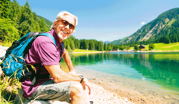 Ein Wanderer mit Rucksack macht Rast an einem Bergsee.