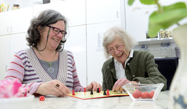 Eine Seniorin spielt mit ihrer Angehörigen "Mensch ärger dich nicht".