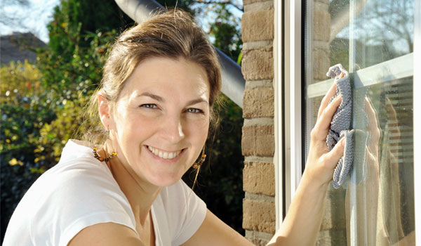 Eine Haushaltshilfe beim Fenster putzen.