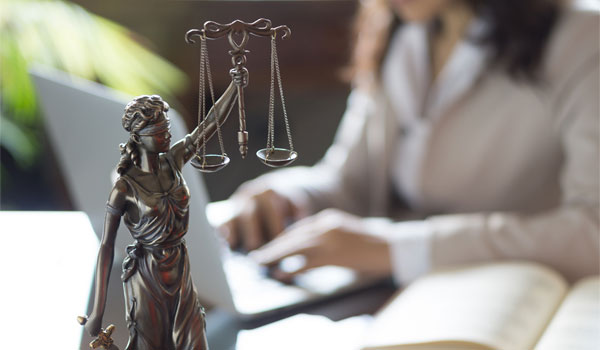 Anwältin arbeitet am Schreibtisch. Vor ihr die Justizia