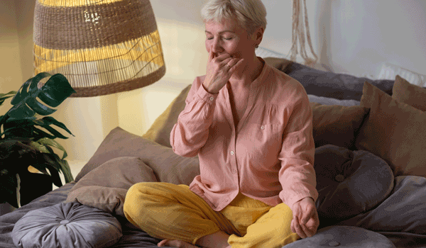 Eine Seniorin mach mal eine Atemübung auf dem Sofa.