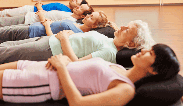 Fünf Personen liegen entspannt auf ihrer Matte.