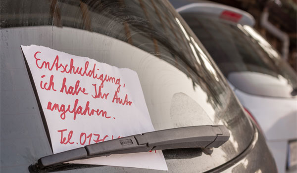 Unfallnachricht an einer Heckscheibe eines Autos.