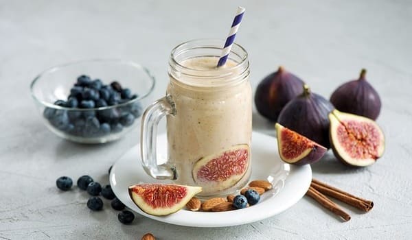 Ein Mahlzeitenersatz mit vielen Früchten in einem großen Glas, als Shake garniert. 