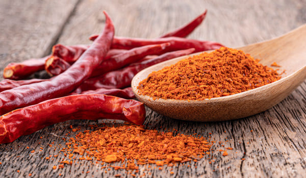 Chili Schoten und Chili Pulver auf einem Holztisch.