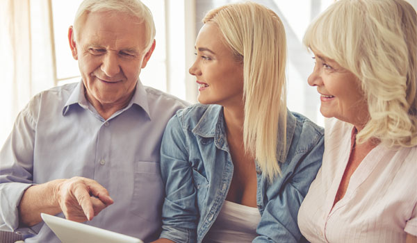 Tochter sitzt mit ihren Eltern vor einem Tablet