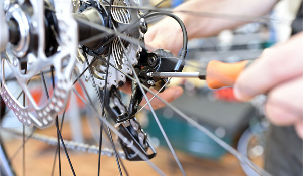 Eine Kettenschaltung wird mit einem Schraubenzieher justiert.