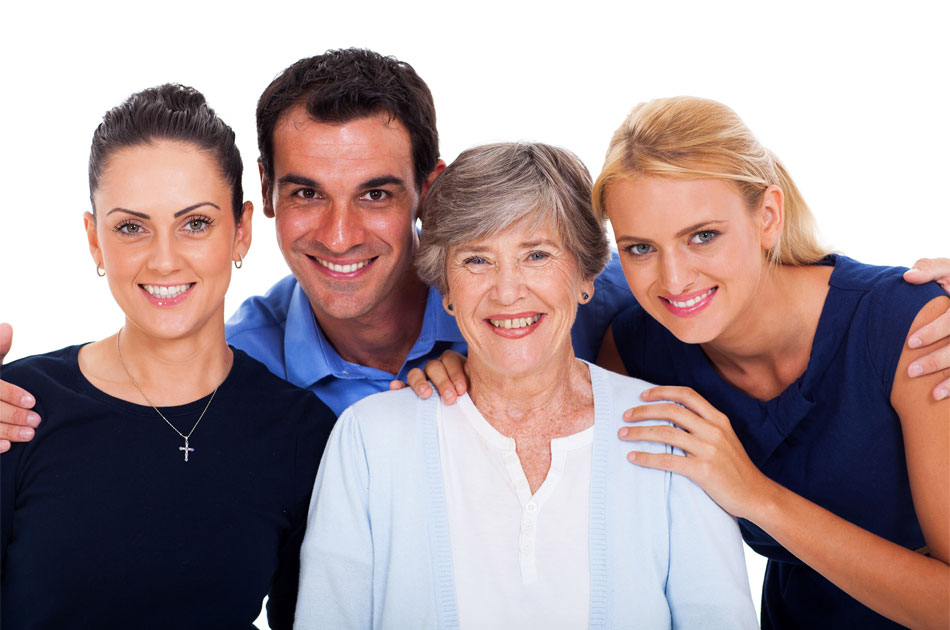 Vier Personen stehen eng beieinander, zwei Frauen und zwei Männer, alle tragen helle oder dunkle Oberteile, eine Frau trägt eine Halskette mit Kreuz.