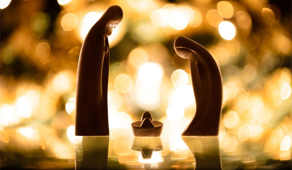 Grippenfiguren vor einem funkelnden Weihnachtsbaum, bei dem nur die Lichter zu erkennen sind.