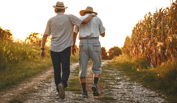 Zwei Männer gehen an einem Feldweg entlang.