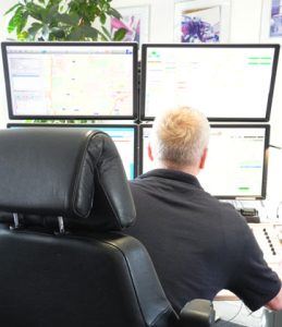 Person sitzt vor vier Bildschirmen, auf denen helle Benutzeroberflächen zu sehen sind.