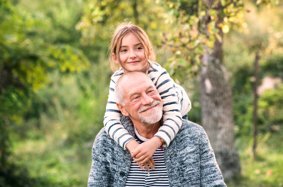 Enkelin auf den Schultern ihres Großvaters unterwegs im Wald.