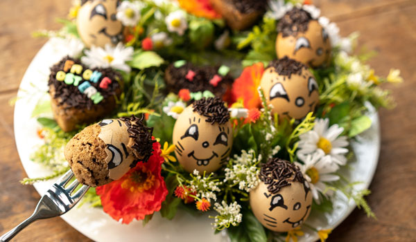 Ein Teller mit ausgeblasenen Eiern, die mit Kuchenteig gefüllt sind.