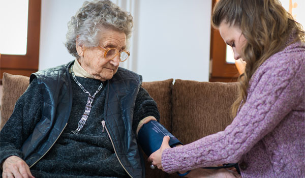 Eine 24 Stunden Kraft misst bei einer älteren Dame den Blutdruck.