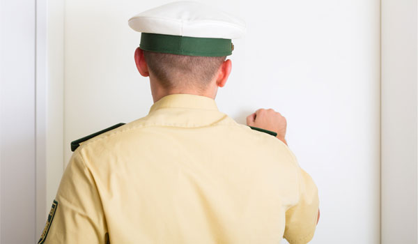 Ein Polizist klopft an die Wohnungstür.