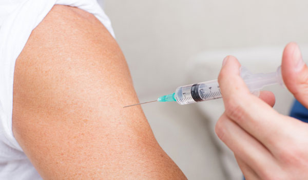 Ein Senior gibt sich eine Spritze in den Oberarm.