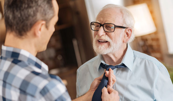 Sohn hilft Vater beim Binden seiner Krawatte.