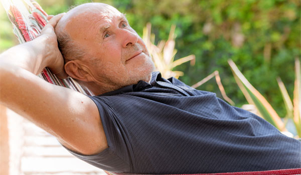 Rentner liegt entspannt auf einer Hängematte.