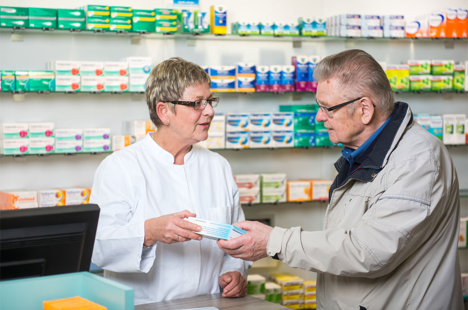 Apothekerin übergibt älteren Herrn sein Medikament