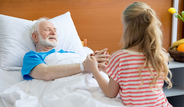 Opa wird im Krankenhaus von seiner Enkelin besucht.