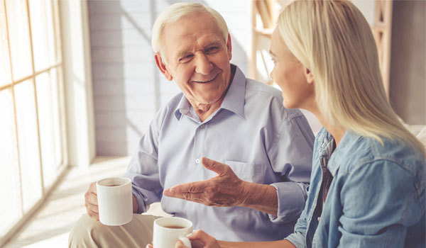 Vater unterhält sich mit seiner Tochter. Beide haben einen Kaffee in der Hand.