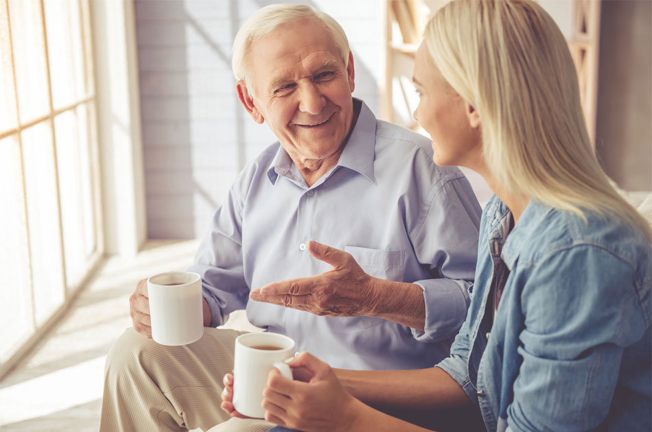 Vater unterhält sich mit seiner Tochter. Beide haben einen Kaffee in der Hand.
