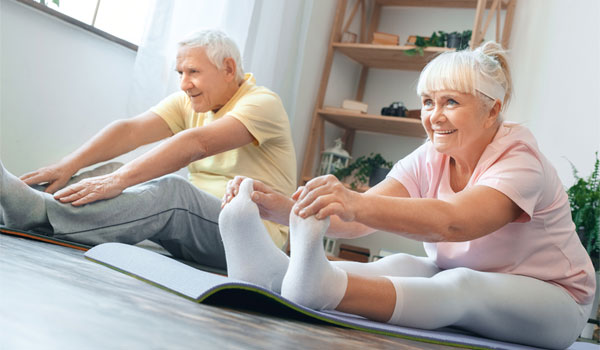 Ein Seniorenpaar macht Gymnastikübungen auf Gymnastikmatten.