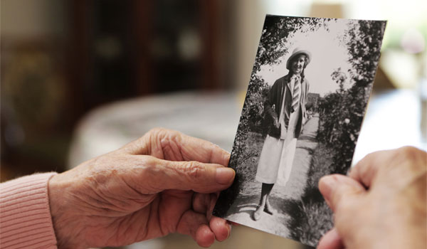 Seniorin mit altem Foto aus ihrer Jugend