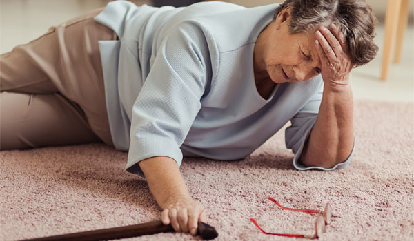 Seniorin ist gestürzt und liegt auf dem Wohnzimmerteppich.