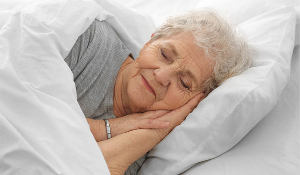 Seniorin liegt im Bett.