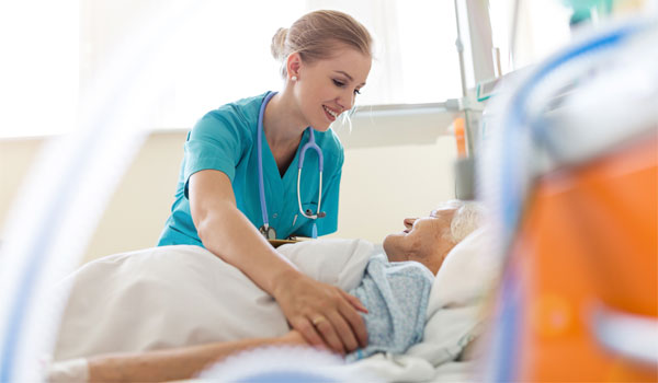 Eine Pflegerin kümmert sich nach der OP um eine ältere Patientin.