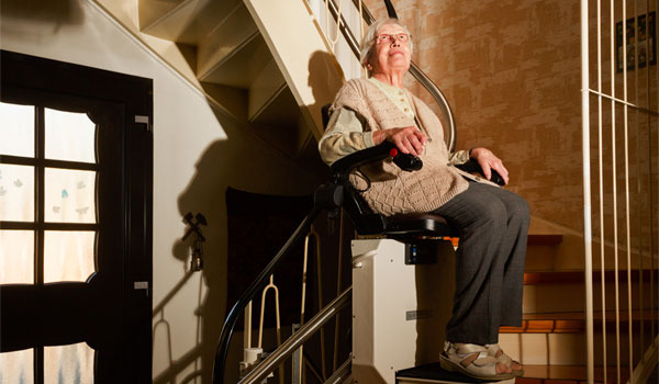 Ältere dame nutzt einen Treppenlift, um in die oberste Etage zu gelangen.