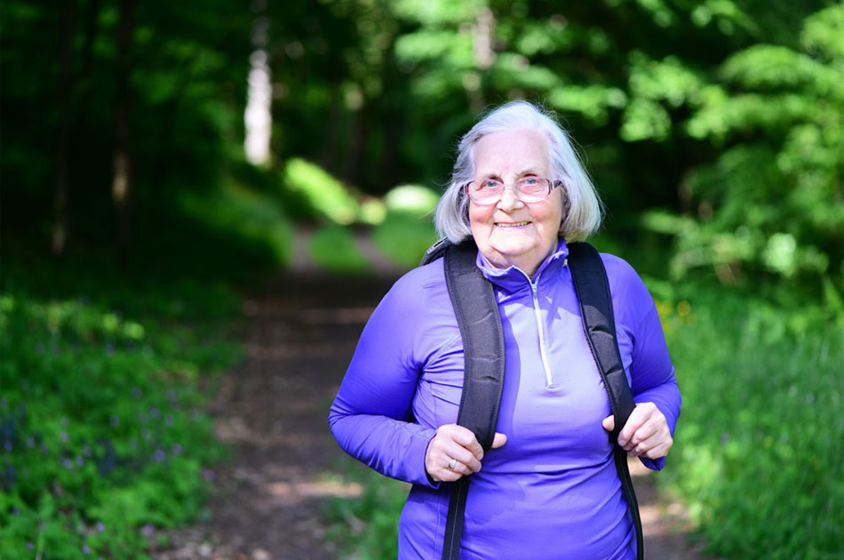 Seniorin unterwegs im Wald beim wandern.
