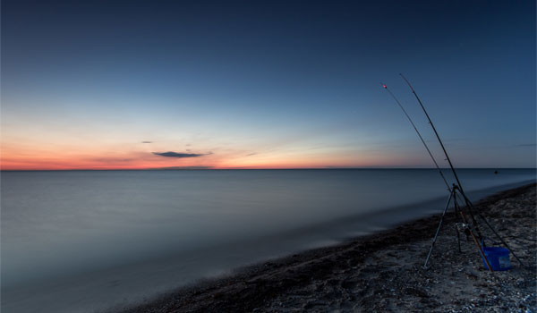 zwei Angeln am Strand in der Nacht