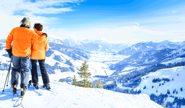 Ein älteres Skipaar genießt die Aussicht auf das verschneite Tal und Berge.die 
