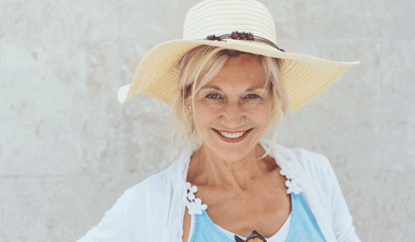 Eine Frau mit Hut und leichter Sommerkleidung genießt das warme Wetter.