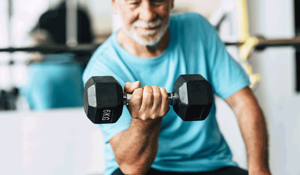 Ein Senior macht Armübungen mit einer Kurzhantel.