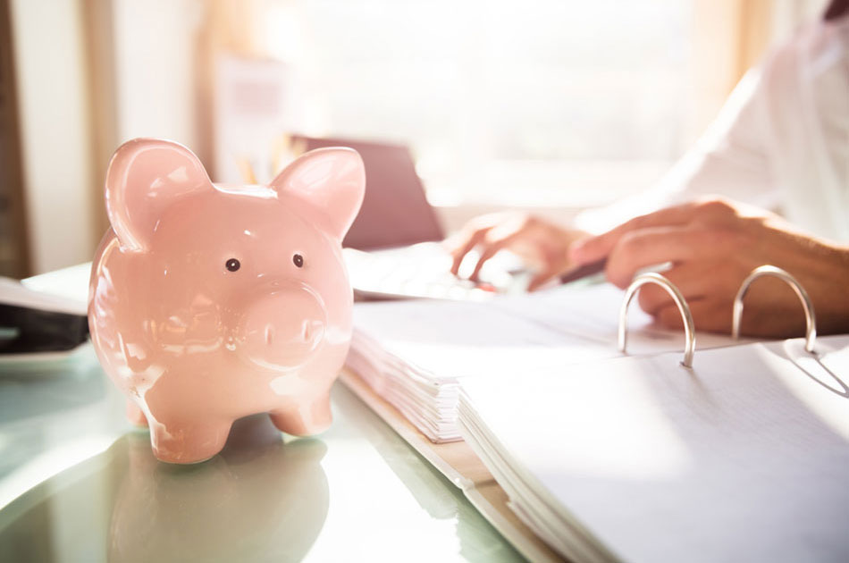 Sparschwein steht auf dem Schreibtisch, während ein pflegender Angehöriger seine Steuererklärung macht.