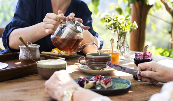 Zwei Personen trinken Tee und essen dazu Kuchen.