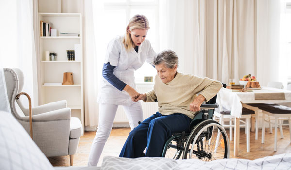 Eine Ersatzpflegekraft hilft einer Seniorin aus dem Rollstuhl.