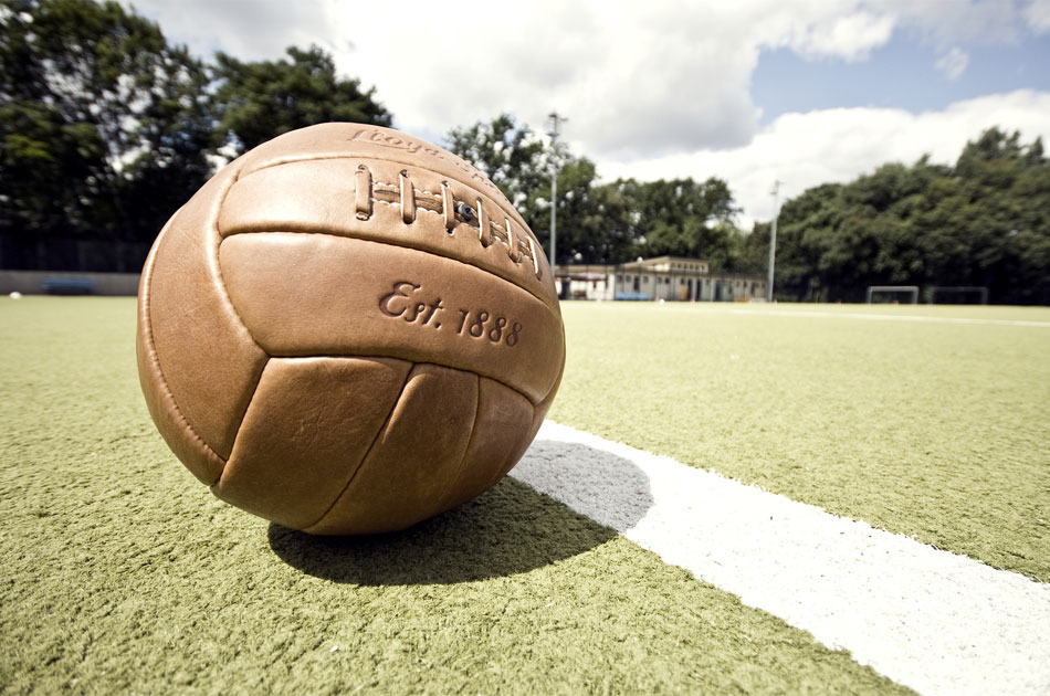 Lederball aus den 50er Jahren liegt auf einem Kunstrasen-Fußballplatz.
