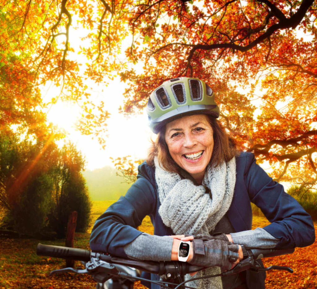Seniorin im Herbst mit dem Rad unterwegs im Wald.