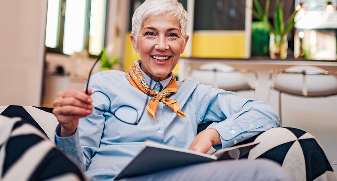 Eine Frau sitzt in ihrem Sessel und liest ein Buch.