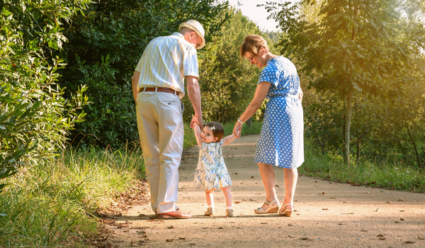 Die Großeltern gehen mit ihrem Enkelkind spazieren.