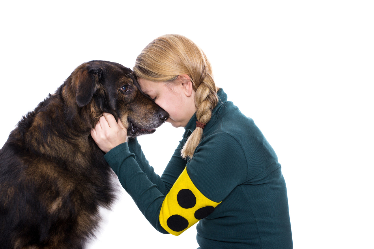 Blinde Frau betastet ihren Blindenführhund und schmust mit ihm.
