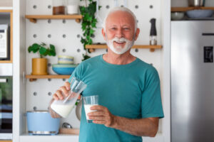 Ein älterer Mann trinkt ein Glas Milch, um keinen Eiweißmangel zu erleiden.
