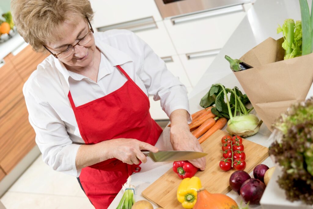 Eine Seniorin kocht eine gesunde Mahlzeit.