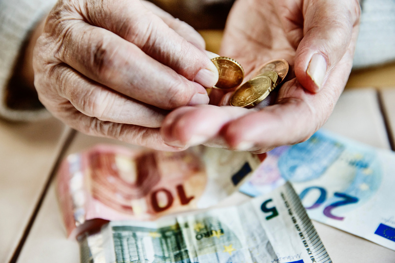 Hand einer Seniorin mit Bargeld, Seniorin zählt ihr Geld.